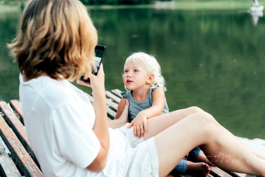 Mom Taking Smartphone Picture of Daughter by the Lake