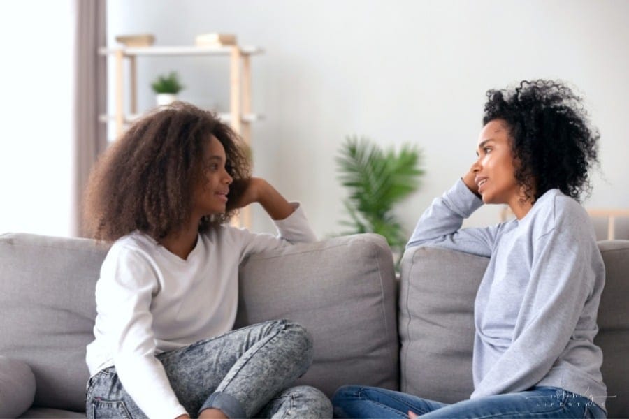 mom and teenage daughter having a conversation on the couch