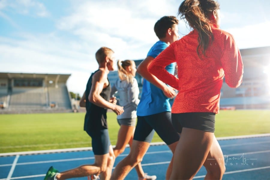 Rear view of young people running together on race track