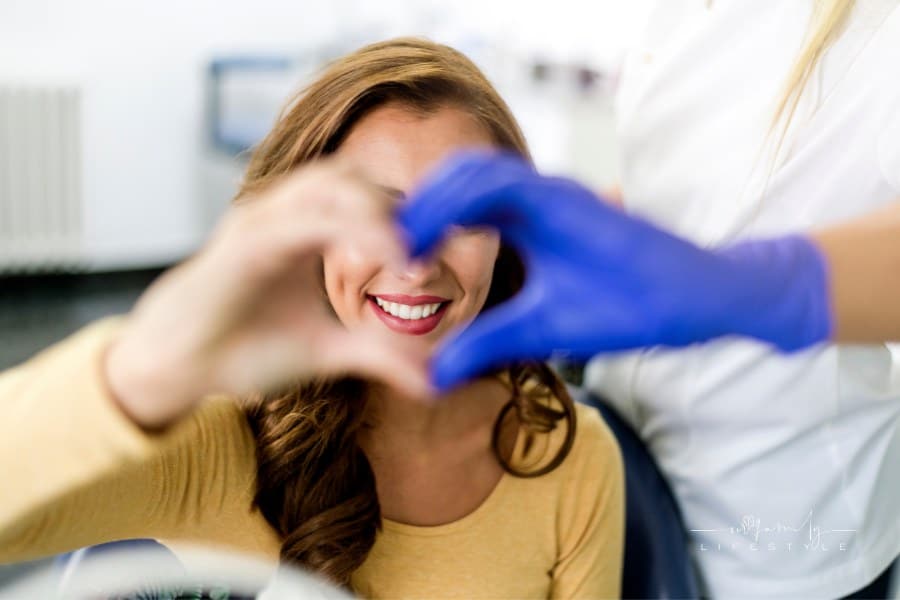 young happy woman patient with woman dentist making a heart with hands