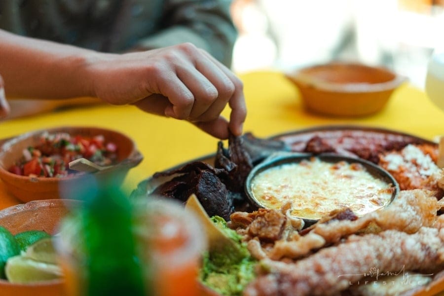 man's hand grabbing a piece of Mexican food dish