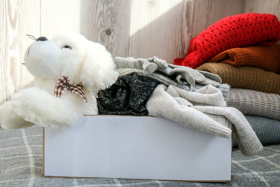 box filled with gently used kids' clothes and stuffed dog
