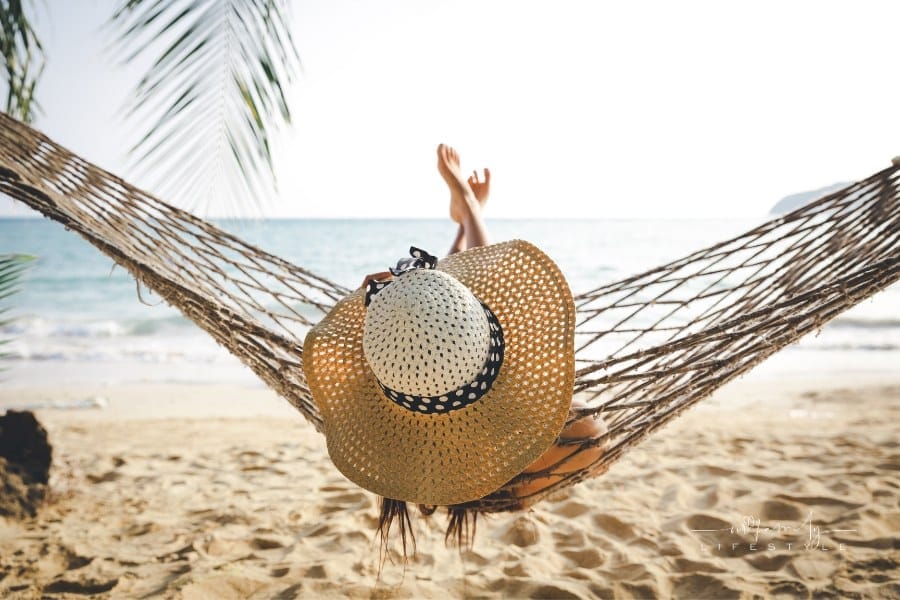 Happy woman relaxing in hammock on a sandy beach