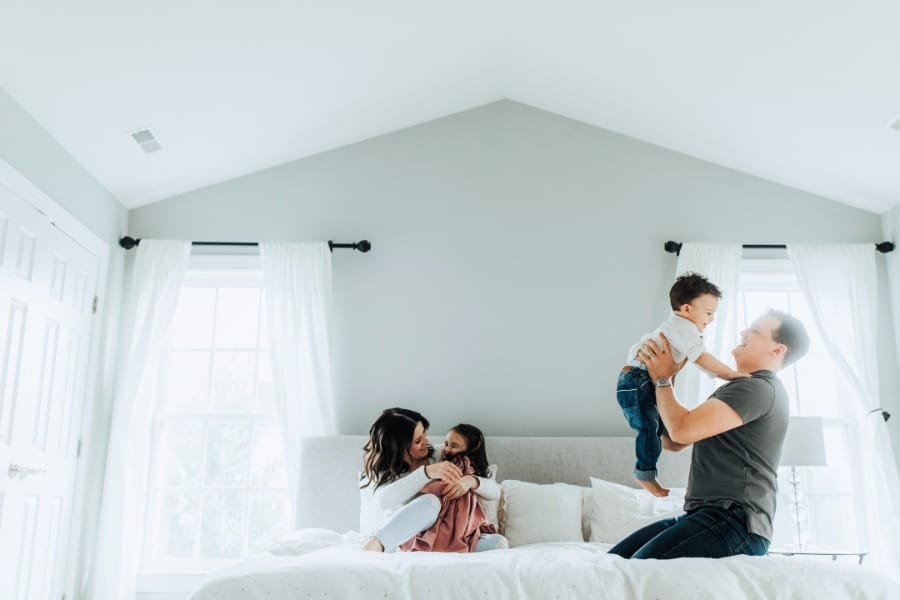 family laughing and playing together in bedroom