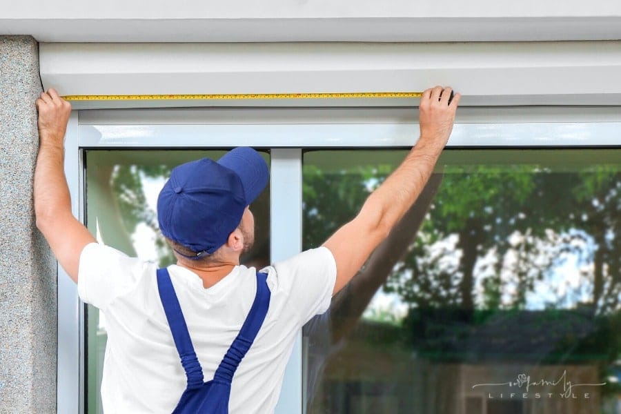 man measuring exterior window prior to installation
