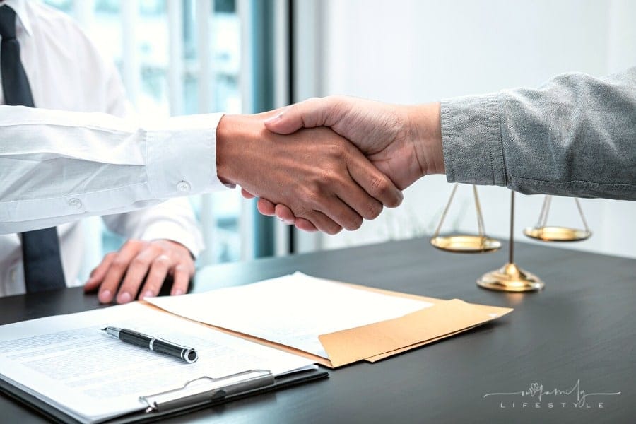 lawyer shaking hands with client over signed contract