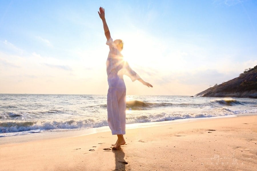 carefree woman dancing in the sun on the beach