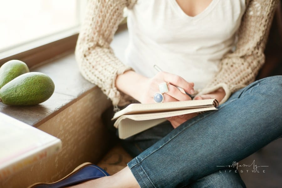 woman journaling next to a window sill